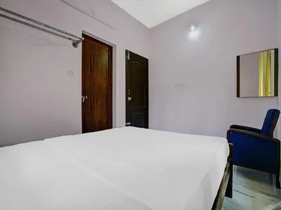 a bedroom with a bed and two blue chairs at Shalom Palace Residency in Neriyamangalam