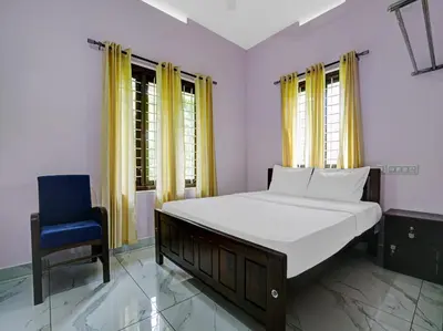a bedroom with a bed and a blue chair at Shalom Palace Residency in Neriyamangalam