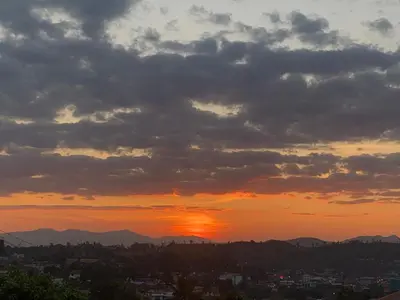 a sunset over a city with mountains in the background at Mercara Aloft in Madikeri