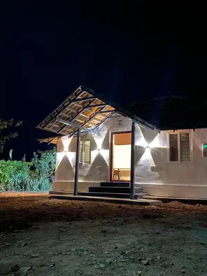 a small white house with a lit up roof at night at Mercara Aloft in Madikeri