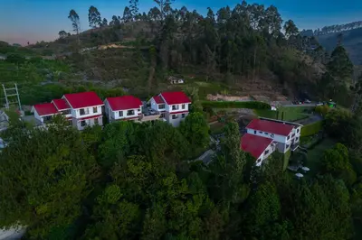 a group of houses with red roofs on a hill at Dvara Luxury Resort Kodaikanal in Kodaikānāl