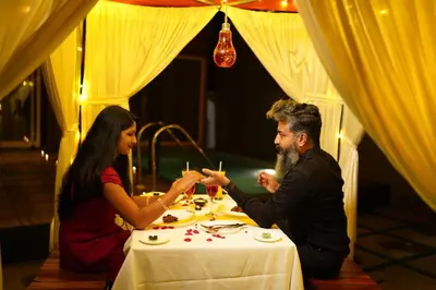 a man and woman sitting at a table with glasses at Mount Stratus Resort Vayalada in Bālūssheri