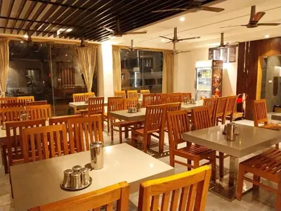 a dining room with tables and wooden chairs at Hotel Nakshathra- A Royal Stay in Palani