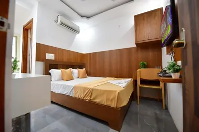 a bedroom with a bed and a desk and a television at Hotel Surya Lodge in Mysore