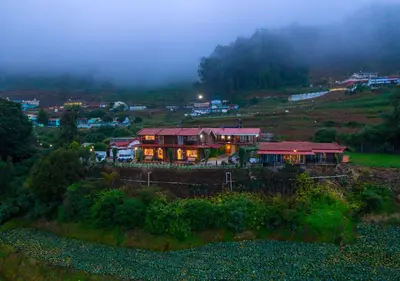 a house on a hill with lights on at SILENT VALLEY FARMSTEAD OOTY by VOYE HOMES in Ooty
