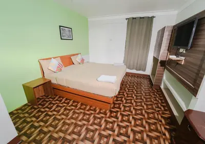 a bedroom with a bed and a flat screen tv at SILENT VALLEY FARMSTEAD OOTY by VOYE HOMES in Ooty