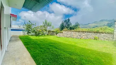 a yard with a stone wall and green grass at Mountain Mansion Kodai in Kodaikānāl