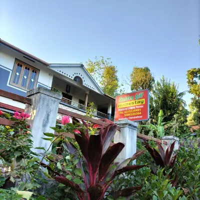 a house with a sign in front of a garden at GOLDEN HILL HOMESTAY WAYANAD in Panamaram