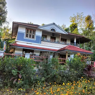 a house with a garden in front of it at GOLDEN HILL HOMESTAY WAYANAD in Panamaram