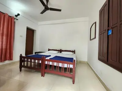 a bedroom with a bed and a ceiling fan at Navarang Villa in Kalpetta