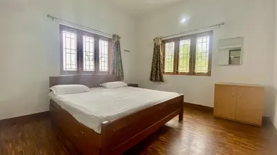 a bedroom with a bed and two windows at Mountain Abode in Kodaikānāl