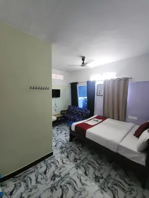 a hotel room with a bed and a couch at Paradise Harmony Beach Resort in Singānallūr