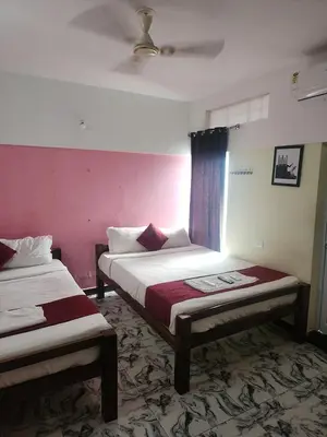 two beds in a room with pink walls at Paradise Harmony Beach Resort in Singānallūr