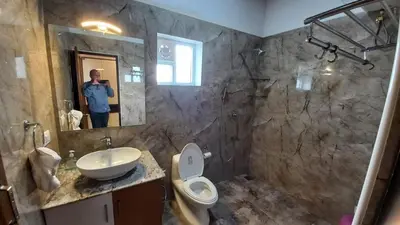 a person taking a picture of a bathroom at Orchard Valley View in Ooty