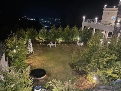 a garden with white tables and trees at night at Orchard Valley View in Ooty