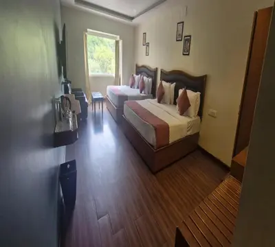 a hotel room with two beds and a window at Hotel Glanton Manor in Ooty