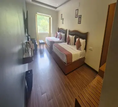 a hotel room with a bed and a desk and a room at Hotel Glanton Manor in Ooty