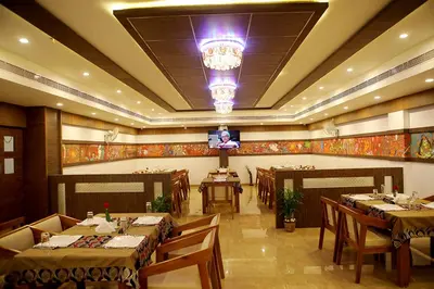 a restaurant with tables and chairs and a chandelier at VKJ INTERNATIONAL in Perumbavoor
