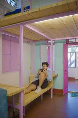 a man sitting on a bunk bed in a room at Rahees Bi Roambay - Backpacker Hostel in Mysore