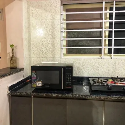 a kitchen with a microwave on a counter at Amberleaf Estate 4BHK Homestay Coorg by Homeyhuts in Virajpet