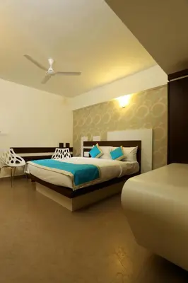 a bedroom with a king sized bed and a chair at moriz inz in Mysore