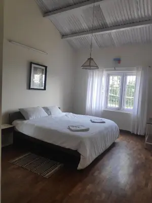 a bedroom with a large bed with white sheets at Dew Drops Cottage Coonoor By Lexstays in Coonoor