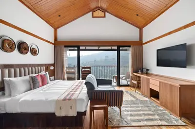 a bedroom with a bed and a flat screen tv at WelcomHeritage Ayatana Ooty in Ooty