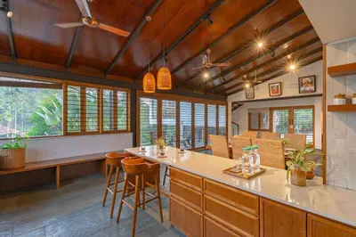a kitchen with wooden ceilings and a bar with stools at StayVista at Mountain Rain - Breakfast Included in Wayanad