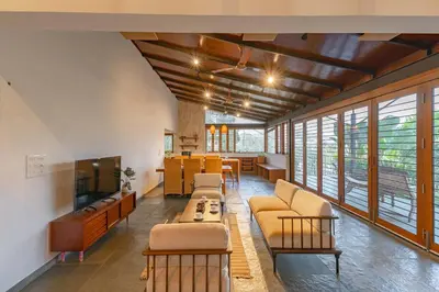 a living room with couches and a tv and windows at StayVista at Mountain Rain - Breakfast Included in Wayanad