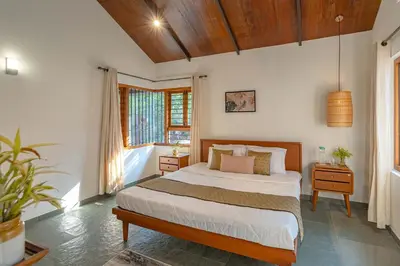 a bedroom with a bed and a window at StayVista at Mountain Rain - Breakfast Included in Wayanad