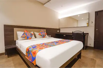 a bedroom with a large white bed with colorful pillows at FabHotel Karpagam - 900m from Nehru Stadium in Coimbatore