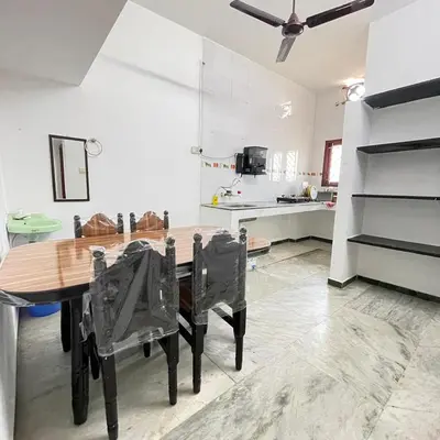 a kitchen with a wooden table and black chairs at WHITE HOUSE - 3BHK Elegant Apartment in Coimbatore