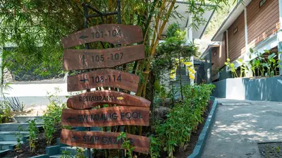 a wooden sign with distances to different plants at The Hive, Wayanad in Wayanad