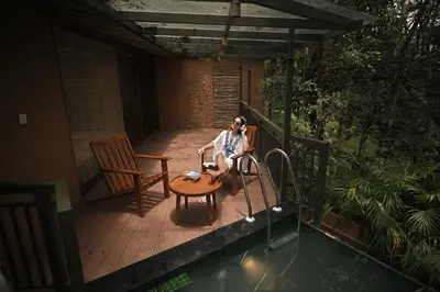 a woman sitting on a deck next to a pool at Chembarathi Wayanad Boutique Resort in Vaduvanchal