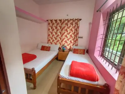 a small bedroom with two beds and two windows at Nakshatra Homestay in Madikeri