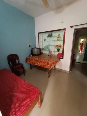 a room with a bed and a table and a window at Nakshatra Homestay in Madikeri