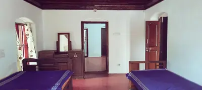 a bedroom with two beds and a dresser and a mirror at Aramana Ayurvedic Wellness Centre & Homestay in Palakkad