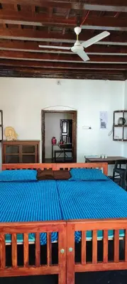 a bedroom with a large wooden bed with blue sheets at Aramana Ayurvedic Wellness Centre & Homestay in Palakkad
