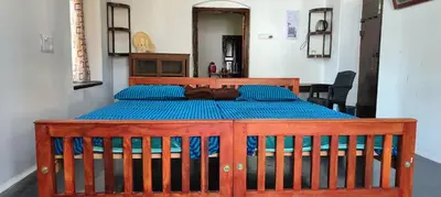 a wooden bed with blue sheets in a room at Aramana Ayurvedic Wellness Centre & Homestay in Palakkad