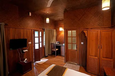 a bedroom with wood paneled walls and a television at Coffee Acres Resort in Kalpetta