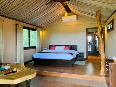 a bedroom with a bed and a tree in it at Niyatma Wayanad Pool Resort by VOYE HOMES - Inside Coffee Plantation in Wayanad