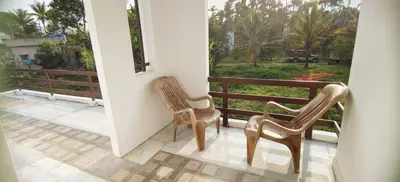 two chairs sitting on a balcony looking out at a yard at Johns Villa in Sultan Bathery