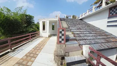 a house with a tile roof with a porch at Johns Villa in Sultan Bathery