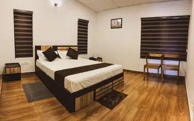 a bedroom with a large bed and wooden floors at PARTHO home stay in Padinjarathara