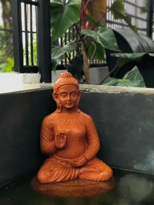 a small statue of a monk sitting on the ground at PARTHO home stay in Padinjarathara