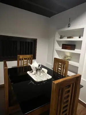 a dining room with a black table and chairs at PARTHO home stay in Padinjarathara