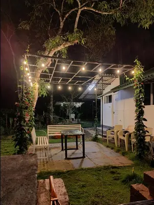 a patio with a table and chairs at night at Multiple Stories, Wayanad in Wayanad