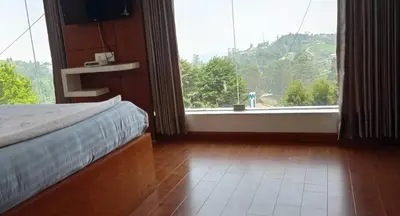 a bedroom with a bed and a large window at Belair Resorts in Kotagiri