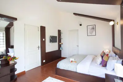 a bedroom with a large bed with a wooden headboard at StayVista at Villa Misty Oaks with Breakfast in Ooty