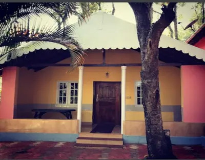 a small house with a palm tree in front of it at Devarakadu Valley View by StayApart in Madikeri